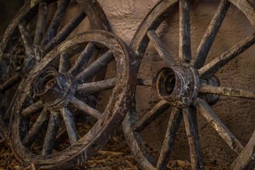 Wooden wheels resting on the wall. Close up of wooden carriage wheels resting on a house wall.