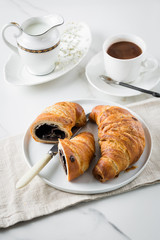 Breakfast with coffee and croissant in white cup and plate on marble background. Healthy homemade pastry, copy space