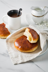 Breakfast with coffee and bun in white cup and plate on marble background. Healthy homemade pastry, copy space