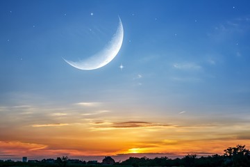 Moon in bright clouds of sunset sun . New moon , moon in the blue sky new moon in the clouds  © yaalan
