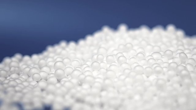 Panning shot of white polystyrene foam beads ball drop from Styrofoam machine for fragile stuff packaging box on blue modern luxury background for decoration