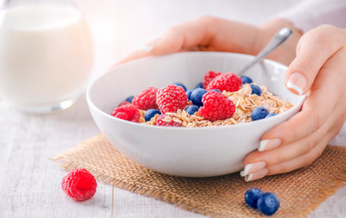 Top view of oat flakes with forest fruits. Raspberries and blueberries in white plate with oat flake