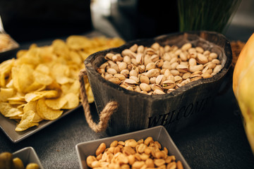 Close up of banquet table with different food Salty snacks. Pretzels, chips, crackers. Walnut, pistachios, almonds, hazelnuts and cashews