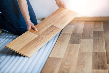Fototapeta na wymiar Worker hands installing timber laminate floor in modern house. Wooden floors renovation