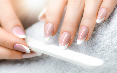 Beautician with nail file. Woman applying nail manicure.