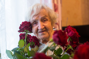 Old woman with flowers in the her house. Granny.