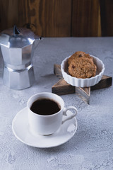 White cup of coffee with oatmeal cookies and coffee maker, breakfast concept, selective focus