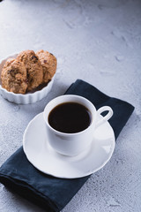 White cup of coffee with oatmeal cookies and coffee maker, breakfast concept, selective focus
