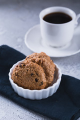 White cup of coffee with oatmeal cookies and coffee maker, breakfast concept, selective focus