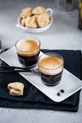 Two cups of fresh espresso on white rectangular tray with milk jar and coffee maker, copy space, breakfast concept 