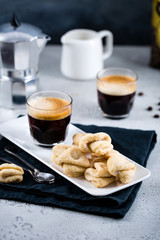 Almond cookies with a cup of fresh espresso on white rectangular tray with milk jar and coffee maker, copy space, breakfast concept 