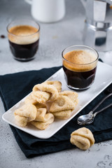 Almond cookies with a cup of fresh espresso on white rectangular tray with milk jar and coffee maker, copy space, breakfast concept 