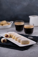 Sweet rolls with jam filling with two cups of fresh espresso with milk jar and coffee maker, copy space, breakfast concept 