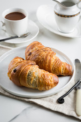 Breakfast with coffee and croissant in white cup and plate on marble background. Healthy homemade pastry, copy space