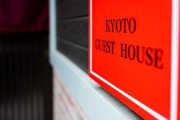 Kyoto residential neighborhood in Japan with closeup of red sign in English for guest house hotel