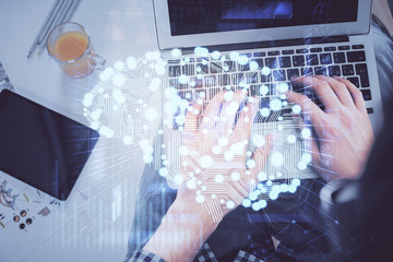 Double exposure of man's hands typing over computer keyboard and brain hologram drawing. Top view. Ai and data technology concept.