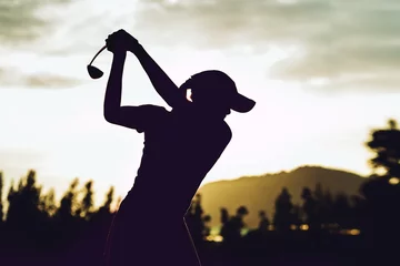 Poster Silhouette of  young professional female golf player hit sweeping and keep golf course doing golf swing,she does exercise for relax time © miraclebuggy