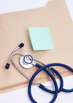 Afile folder, a stethoscope and a pen on ekg