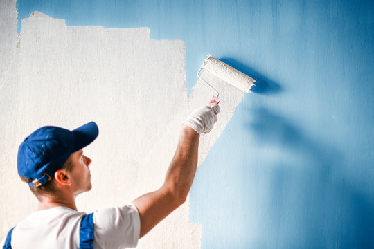 Painter Painting A Wall With Paint Roller.