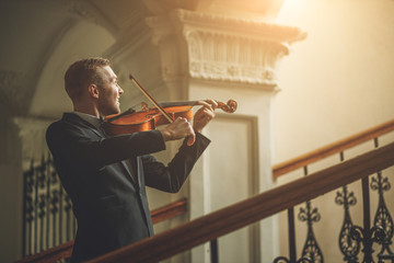 young caucasian musician violinist perform music in the hall before concert, practice playing...