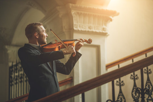 young caucasian musician violinist perform music in the hall before concert, practice playing violin. classical instruments, music concept - Powered by Adobe