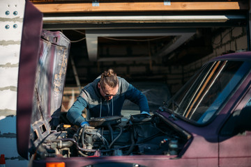 A man repairs a car, opens the hood