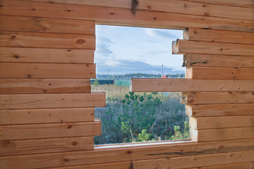 Wall from timber with window of unfinished construction of wooden house