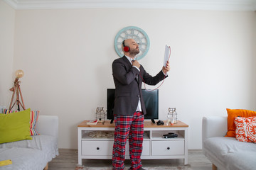 young bearded man with sweatpants on top of a suit, talking to his delighted friends listening to...