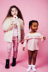 lifestyle people concept: diverse nation children playing together, caucasian and african american on pink background