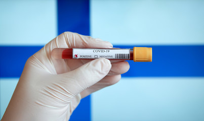 COVID-19 Pandemic Coronavirus concept ; Close-up of a Positive COVID-19 blood test sample tube with Flag of Finland at background. Blood testing for diagnosis new Corona virus infection.