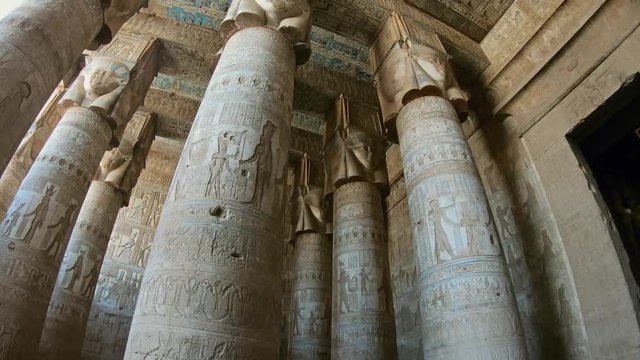 Interior of the painted and carved hypostyle hall at Dendera Temple. Ancient Egyptian temple near Qena. Tilt view 4k