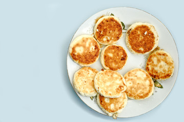 Fototapeta na wymiar curd pancake on a white plate. blue table background.