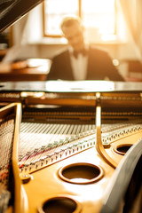 close-up photo of piano, young man playing on it, performing classical music