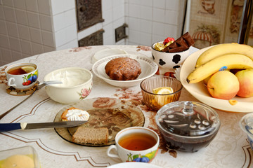 a dining table in the village. on the table is sour cream, apples, bananas, pies with sweets, curd pancake.