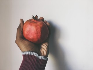 Cropped Hand Of Person Holding Pomegranate On Table