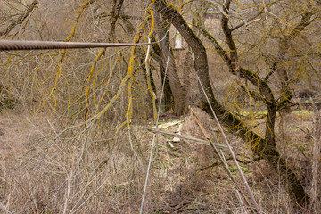 Broken old pedestrian bridge in the countryside, metal cables without boards
