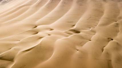 Aerial top-down view of sand dunes. Sand dunes create abstract shapes during the day light. Wind formations.