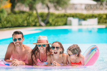 Happy family of four in outdoors swimming pool - 338201120