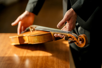 cropped unrecognizable professional musician taking violin in hands, going to perform classic music, violinist, music concept