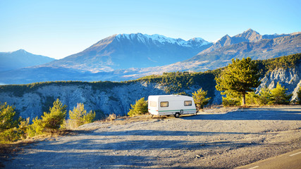 Caravan trailer stucked near the border of Italy because of travel ban, close-up. Coronavirus (COVID-19) outbreak, quarantine zone in France. An empty highway in a French Alps mountains on a clear day
