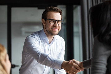 Smiling middle-aged male employee shake hand close deal make agreement with female coworker at meeting, happy businesspeople handshake get acquainted or greeting with success at briefing