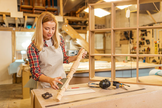 young hardworking skillful carpenter woman grinding piece of wood, handicraft maker, awesome woodworker behind workbench