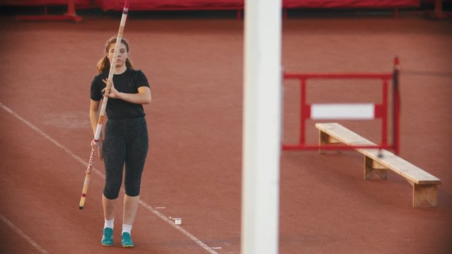 Pole vault training on the stadium - woman running up and jumping over the bar touching it