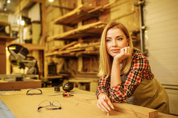 side view on beautiful woman after work, female work as carpenter in factory. stand next to desk, think