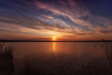 Fototapeta premium Beautiful sunset on the lake with clouds and reflections on the water