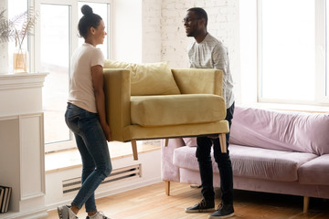 Young happy african american couple moving and carry table. Attractive family of diverse woman and...