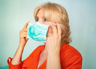 Older woman putting on surgical mask correctly , without touching face too much, Coronavirus, epidemics.