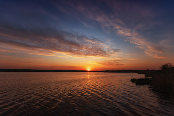 Beautiful sunset on the lake with clouds and reflections on the water