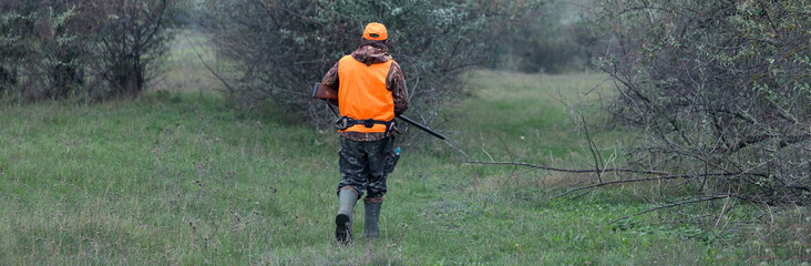 Hunter with a gun and a dog go on the first snow in the steppe, Hunting pheasant in a reflective...