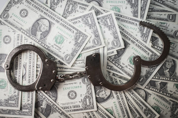 handcuffs sitting on top of US paper currency